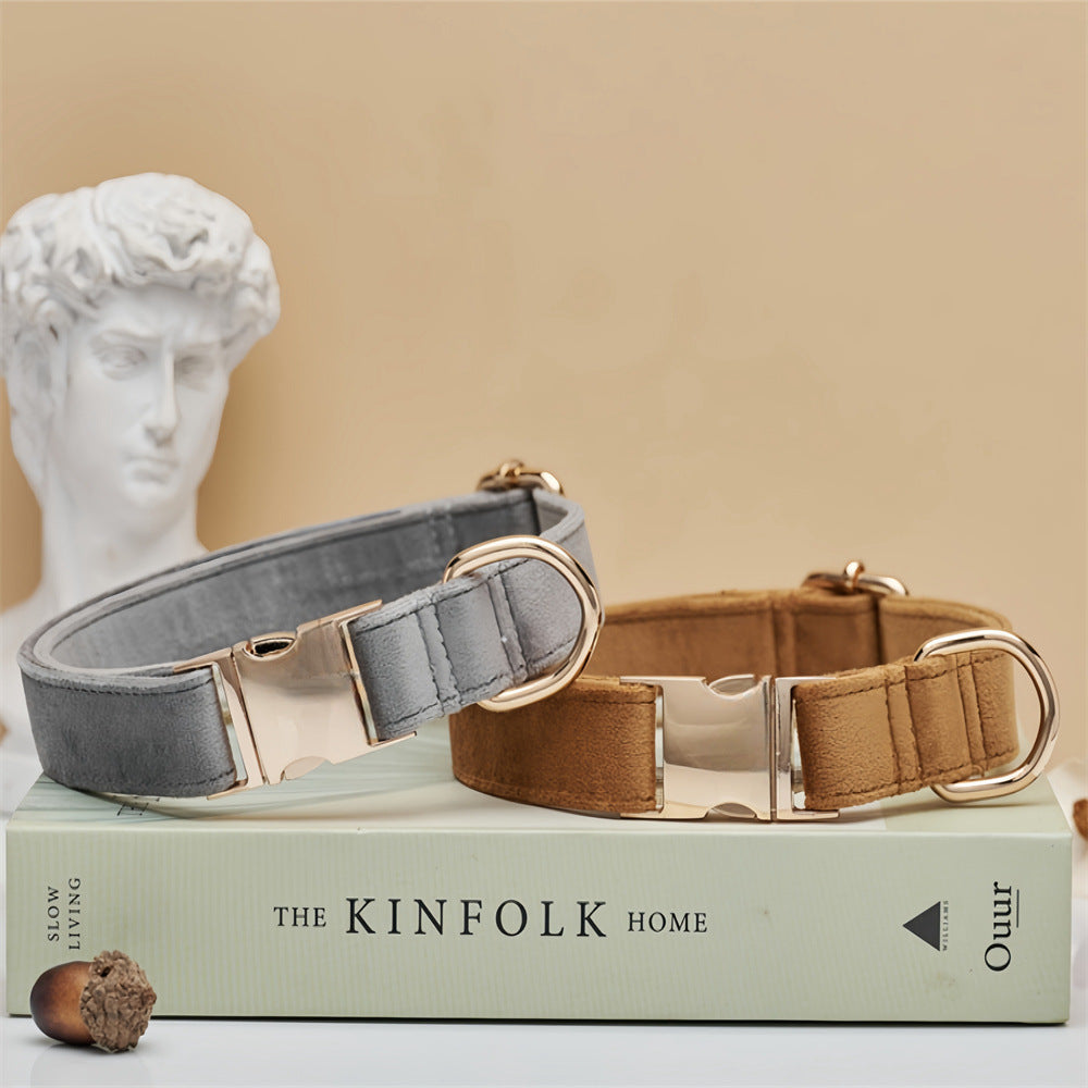 Two dog collars, one gray and one brown, on a book titled 'The Kinfolk Home' with a classical statue in the background.