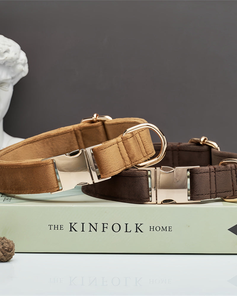 Two dog collars on a book with 'The Kinfolk Home' title, a classical statue head in the background.