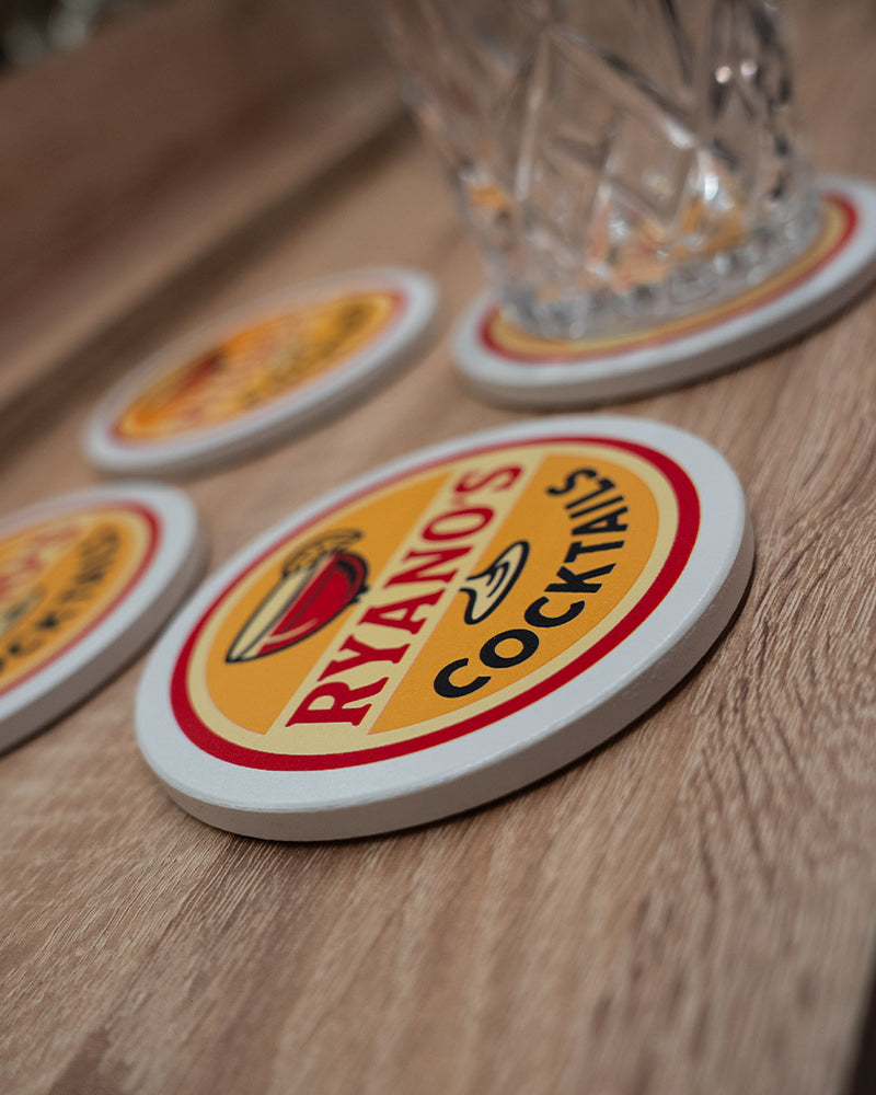 Coasters with 'Ryan's Cocktails' logo on a wooden surface