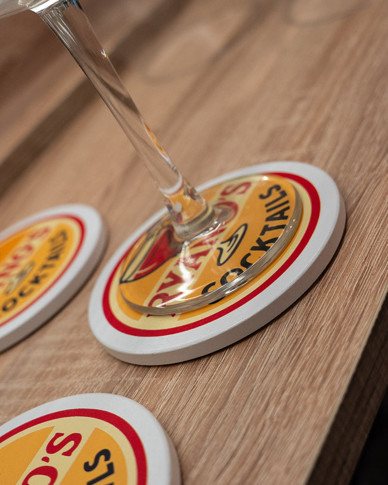 Glass of champagne on a coaster with a brand logo on a wooden surface