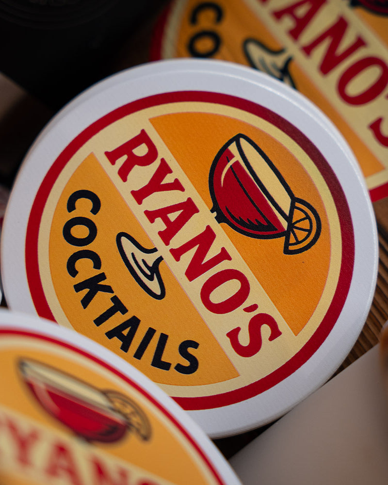 Close-up of 'Ryanos Cocktails' coasters with a blurred background