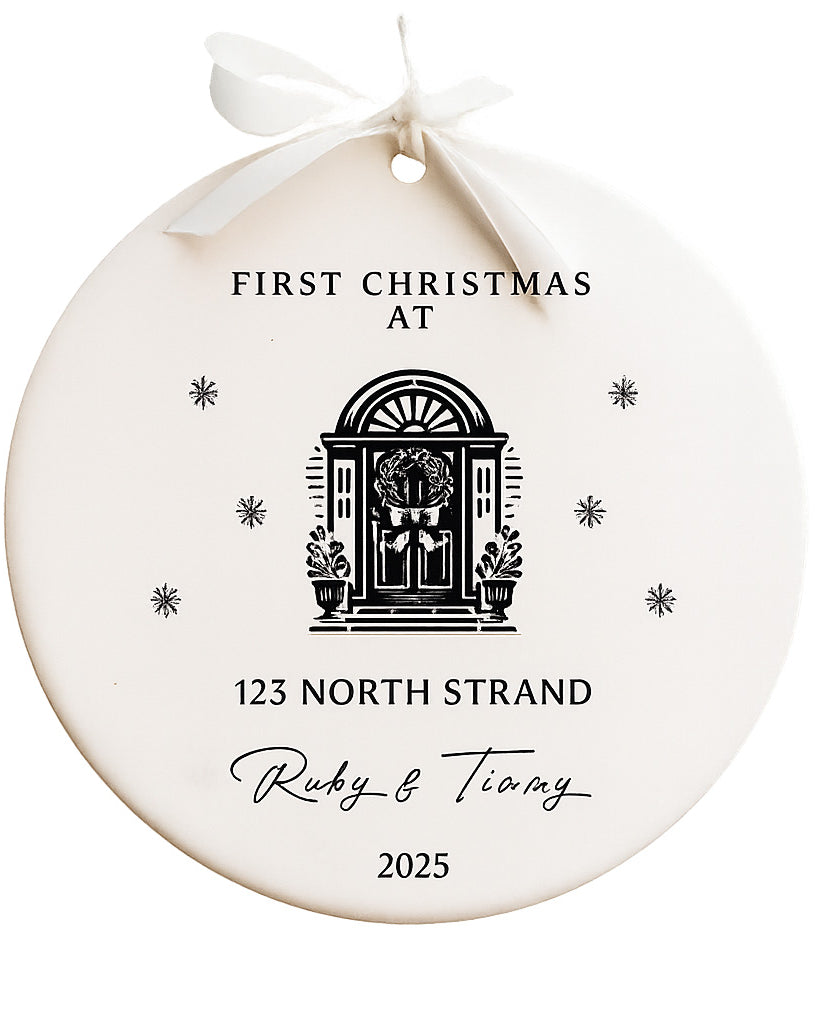 Round white ornament with black text and a door illustration, tied with a white ribbon on a white background.