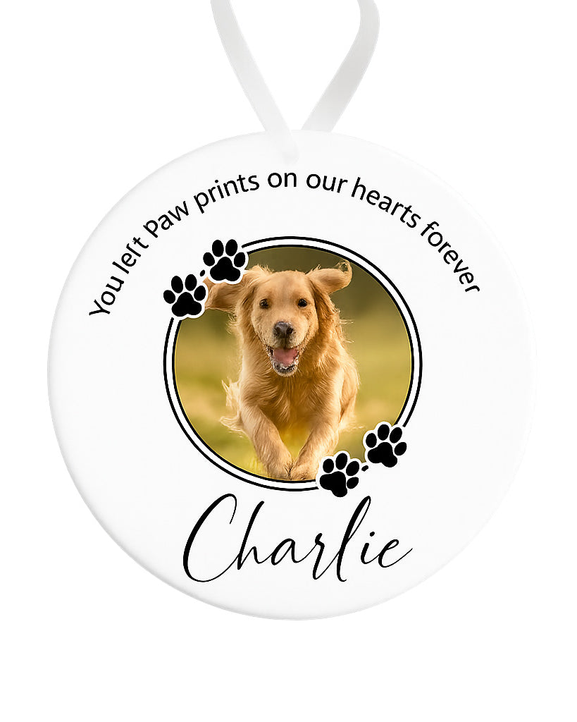 Memorial ornament with a photo of a dog and text 'You left paw prints on our hearts forever Charlie' on a white background.
