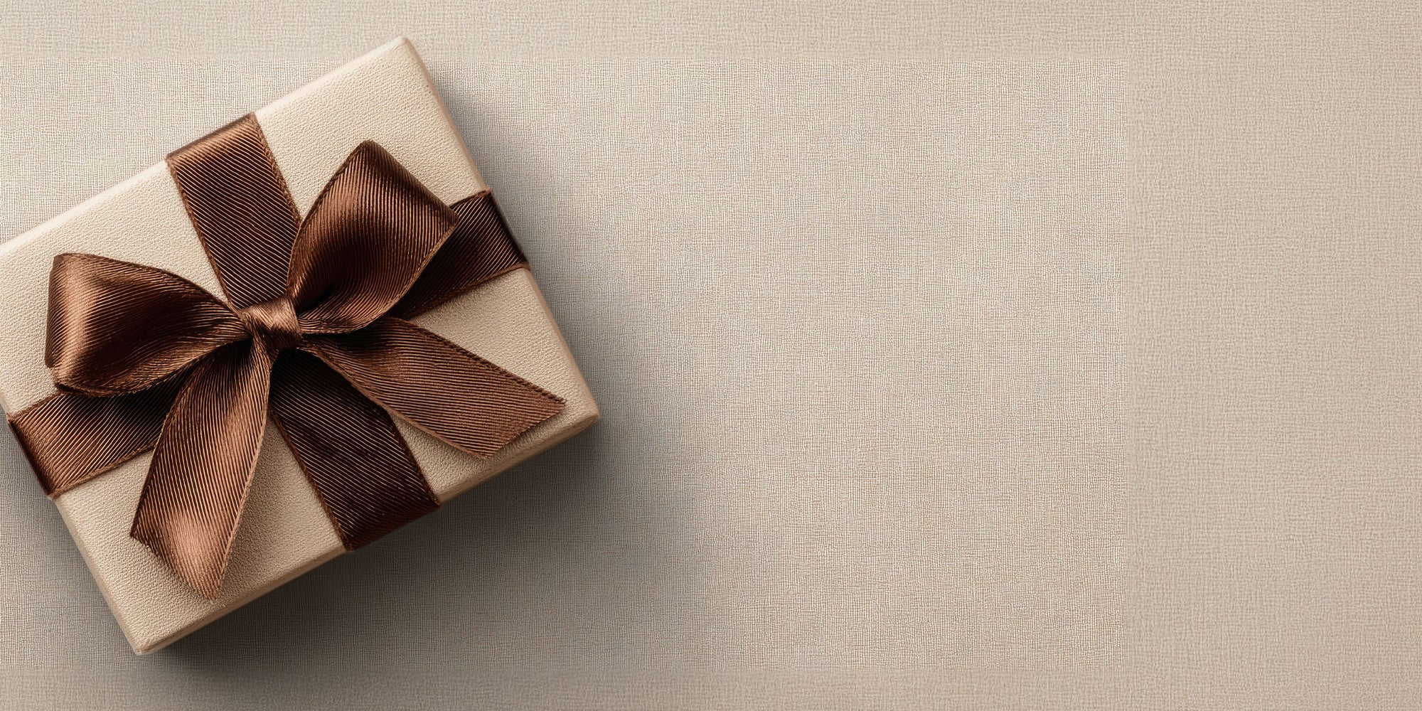 Gift box with a brown ribbon on a beige background