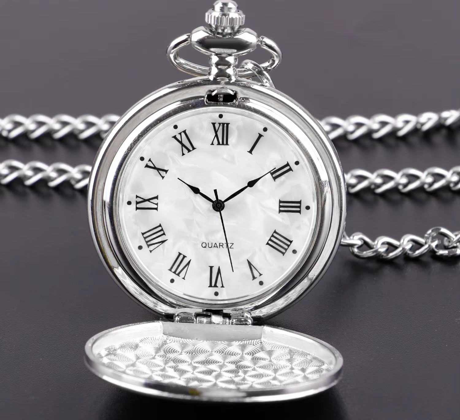 Silver pocket watch with Roman numerals on a dark background