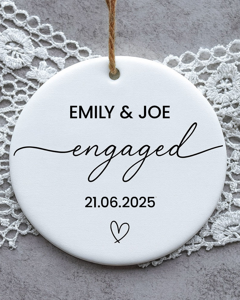 Round ceramic disc with 'EMILY & JOE engaged 21.06.2025' text on a lace background