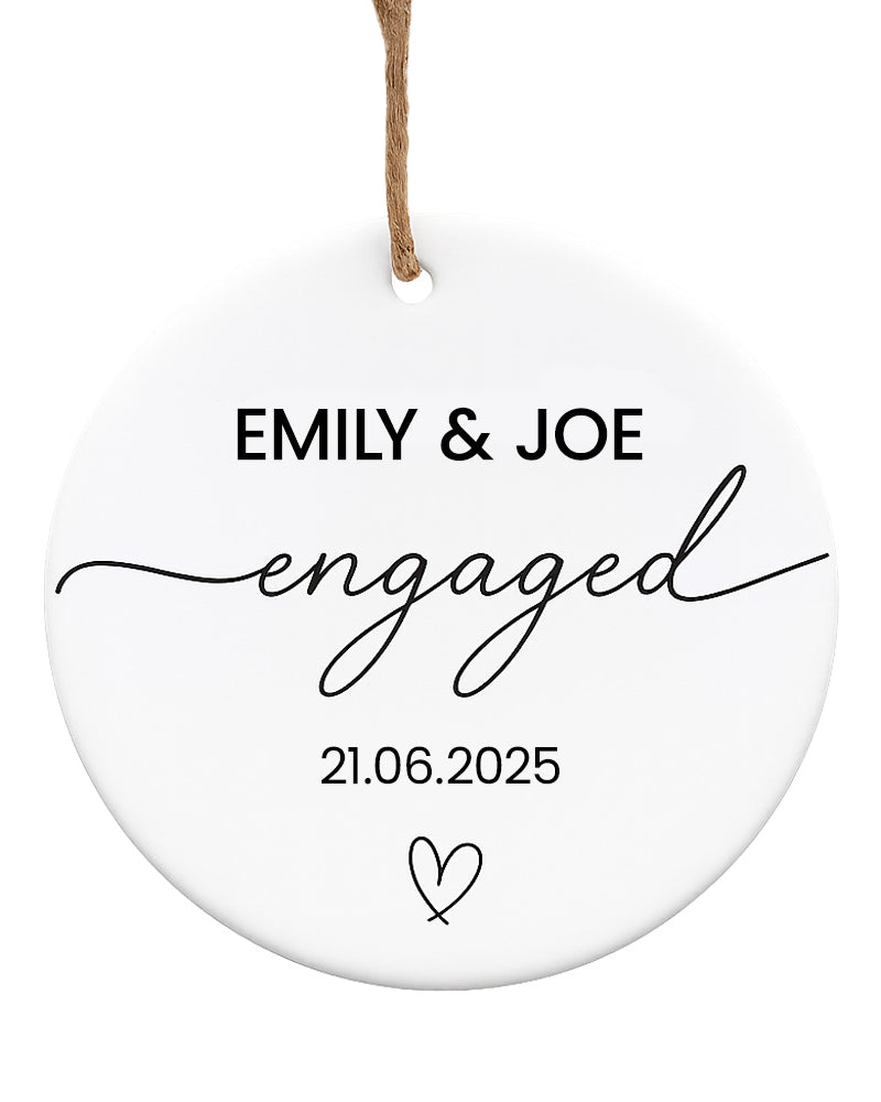 Round white ornament with 'EMILY & JOE engaged' text and date on a white background