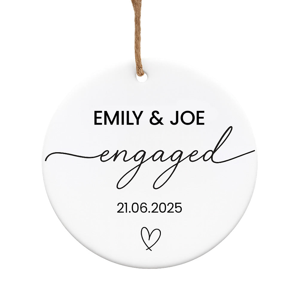 Round white ornament with 'EMILY & JOE engaged' text and date on a white background