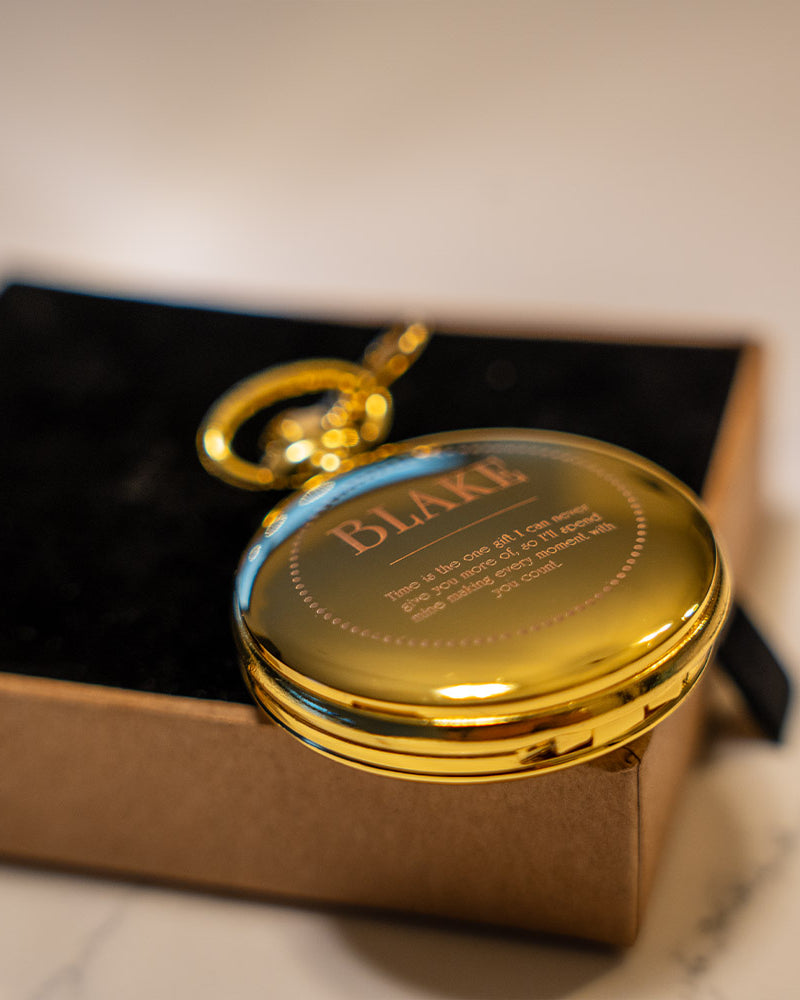 Gold pocket watch with 'BLAKE' engraving on a marble surface