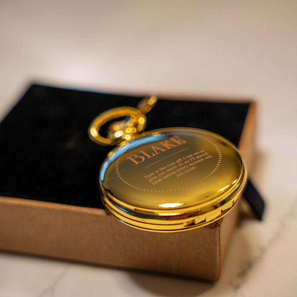 Gold pocket watch with 'BLAKE' engraving on a marble surface