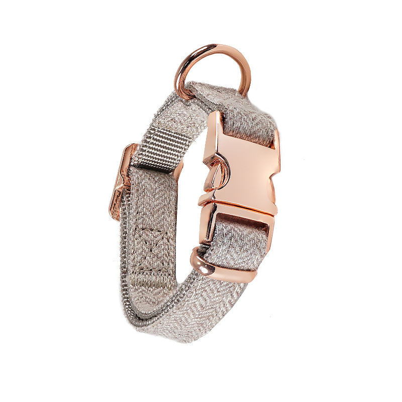 Grey herringbone dog leash with rose gold clasp, coiled on a white background.

