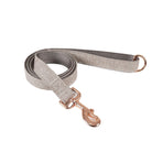 Grey herringbone dog leash with rose gold clasp, coiled on a white background.

