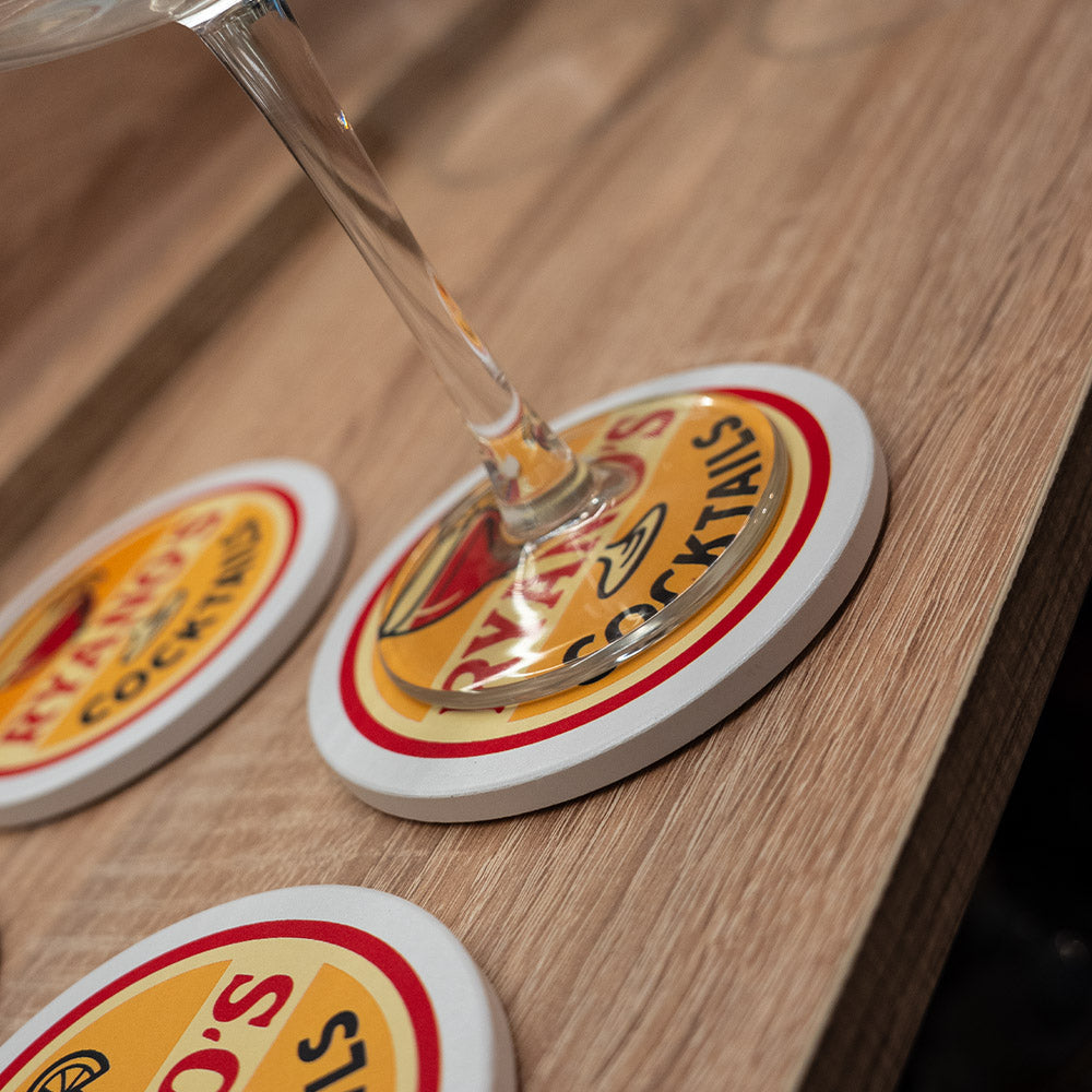 Glass of champagne on a coaster with a brand logo on a wooden surface