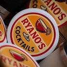 Close-up of 'Ryanos Cocktails' coasters with a blurred background
