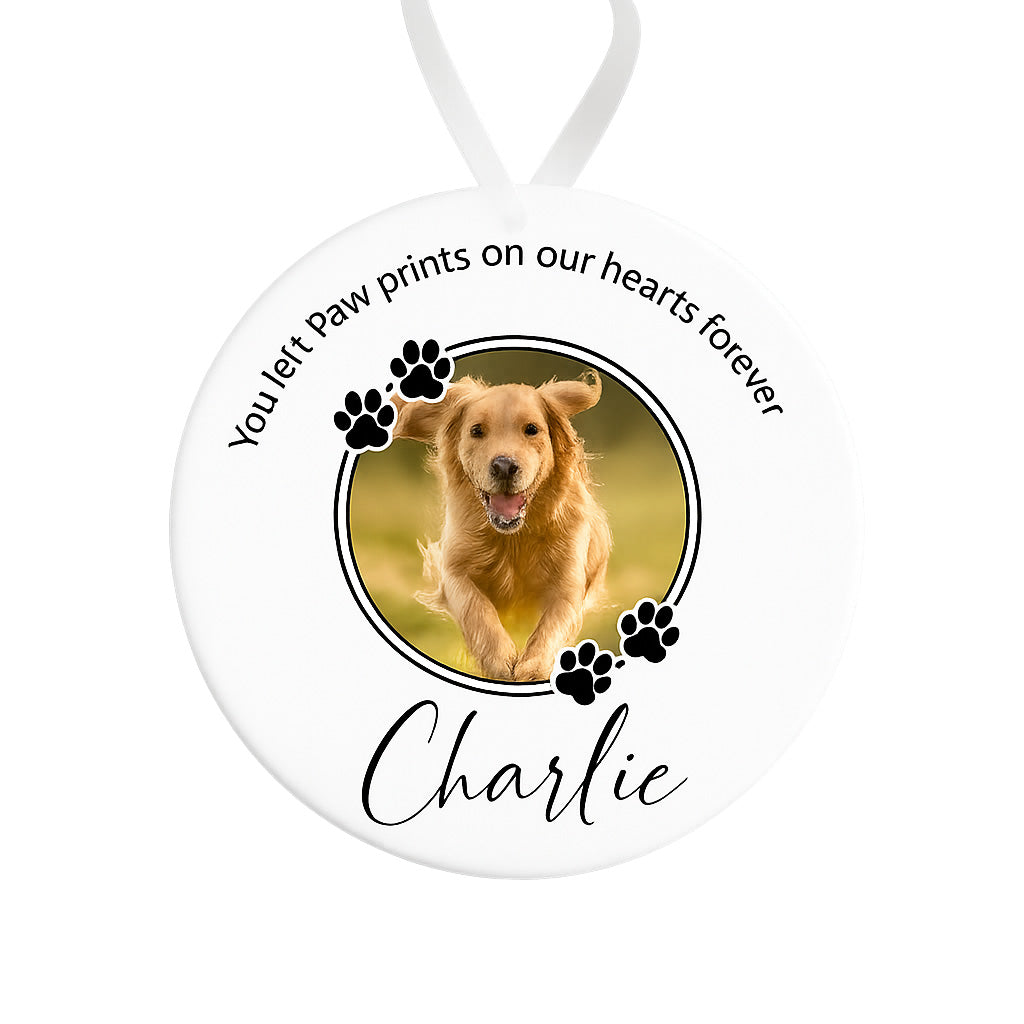 Memorial ornament with a photo of a dog and text 'You left paw prints on our hearts forever Charlie' on a white background.