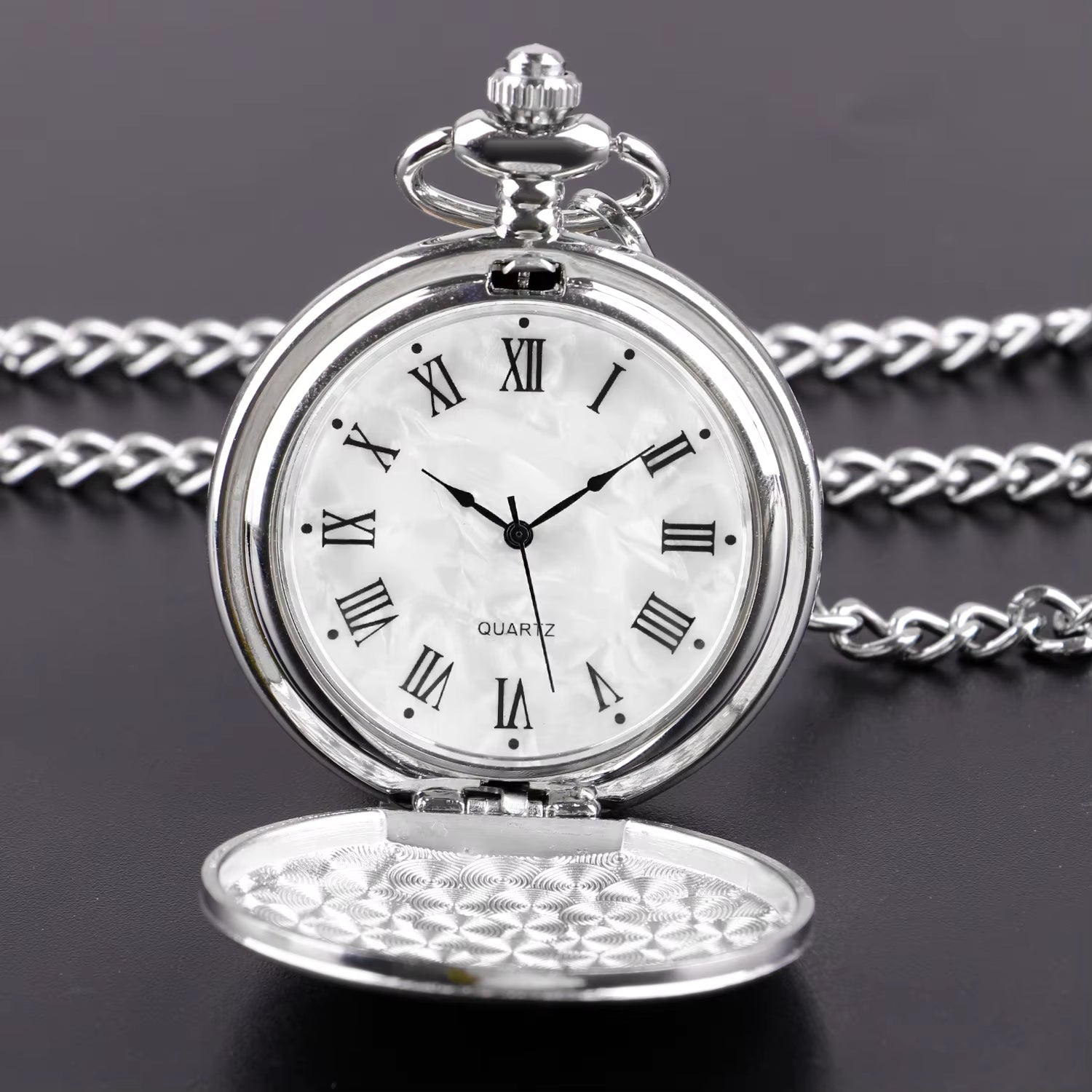 Silver pocket watch with Roman numerals on a dark background