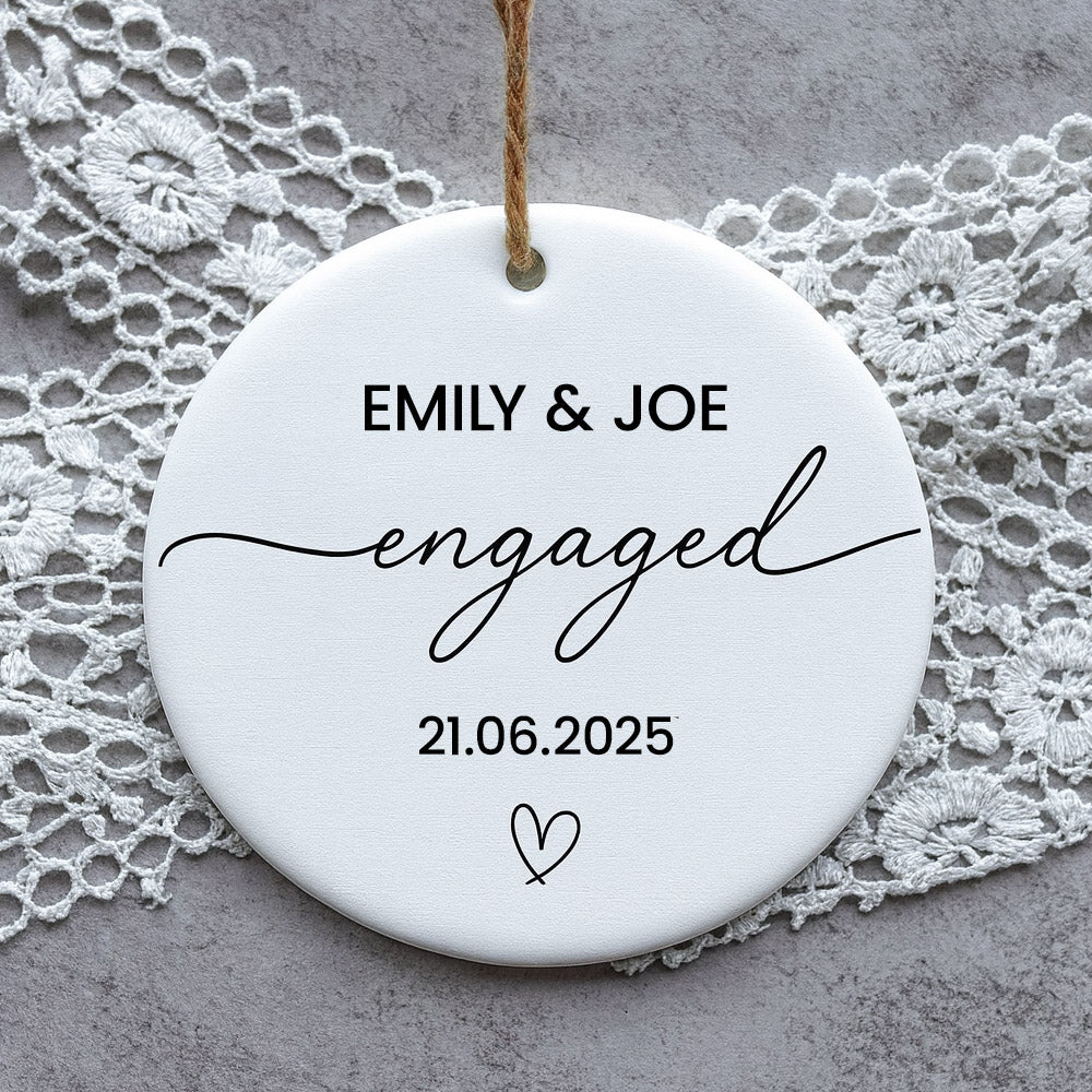 Round ceramic disc with 'EMILY & JOE engaged 21.06.2025' text on a lace background