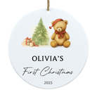 Decorative Christmas ornament with a teddy bear, tree, and presents, featuring 'Olivia's First Christmas 2025'.